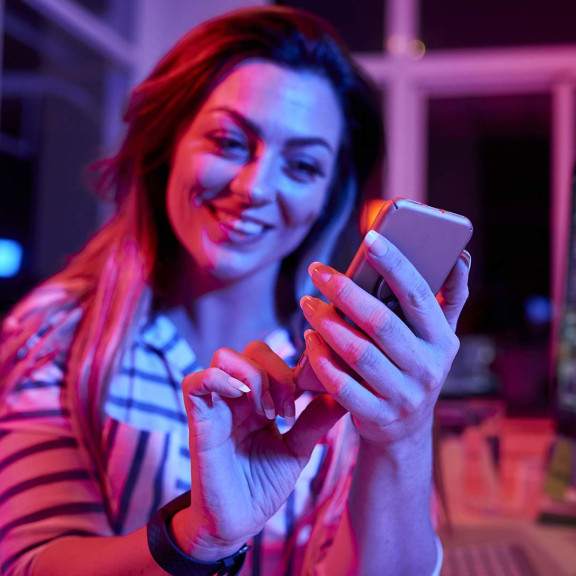A woman scrolls on her mobile phone while smiling.