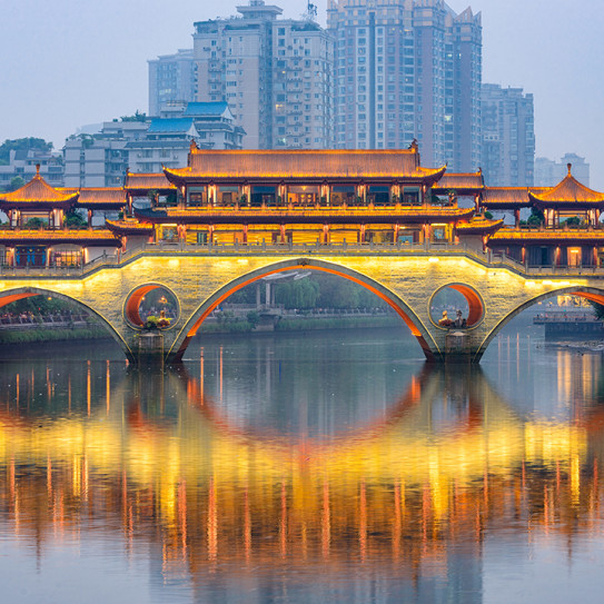 Un pont lumineux traverse une rivière dans une ville d'Asie