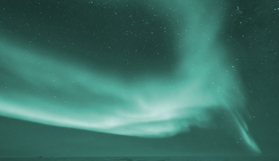 Green aurora borealis on the night sky above the sea