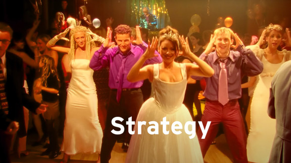 Still of people dancing from a videoclip with the word strategy in bold letters