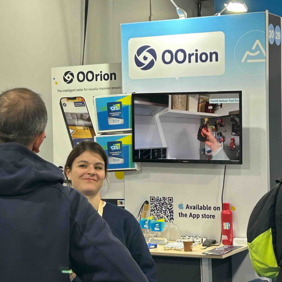 Deux personnes situées sur le stand de la start-up OOrion discutent