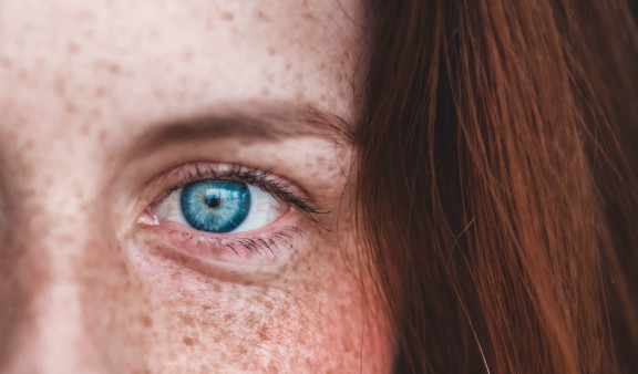 A human blue eye of a woman with freckles
