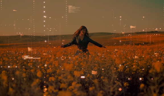 A woman happily dances in a field of flowers.