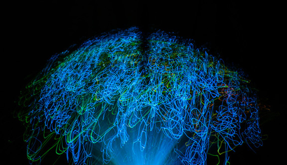 Du light painting bleu et vert sur un fond noir représente un cerveau pour illustrer l'intelligence artificielle