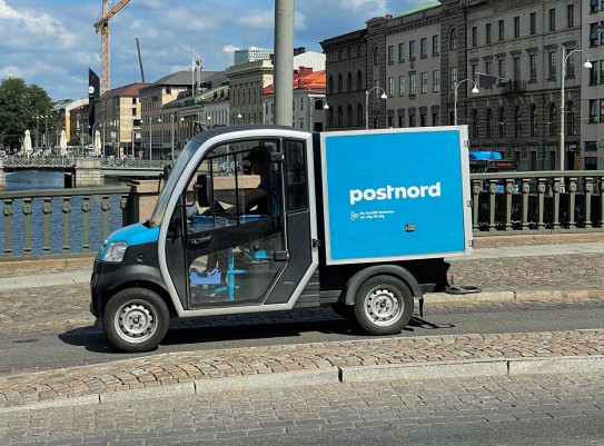 Postnord courier out for delivery in an electrical vehicle